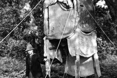 George Boast a Gamekeeper stands next to bird hide erected for photographing a Nuthatch, Eric Hosking can be seen looking out from the hide - year 1930
